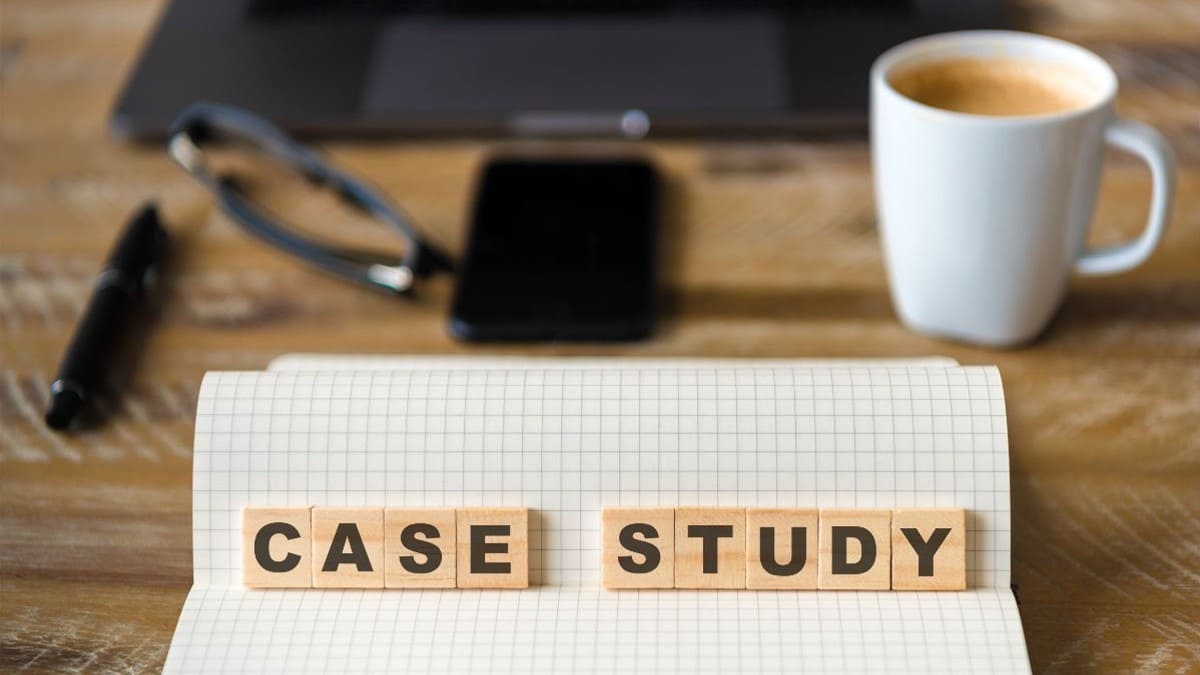 仕事中のPCを遠景とし「CASE STUDY」という文字が書かれた木製のブロックが置かれたノートが手前に置かれている